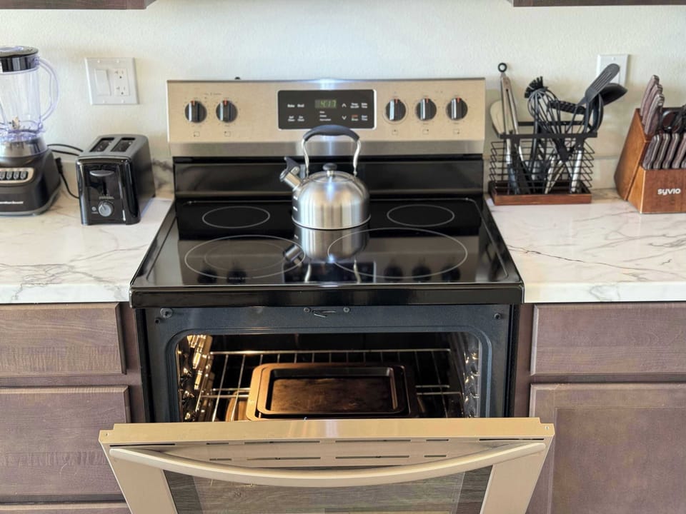 Complete kitchen setup ideal for extended stays: stovetop, fridge with freezer, microwave, blender, toaster, kettle, coffee machine, pots, pans, and utensils provided.