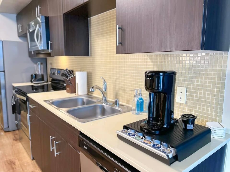 Modern kitchen ideal for extended stays, featuring a stovetop for cooking versatility, a microwave for quick meals, and a kettle for hot beverages. Complete with essential cookware including pans, pots, a knife set, and a handy chopping board.