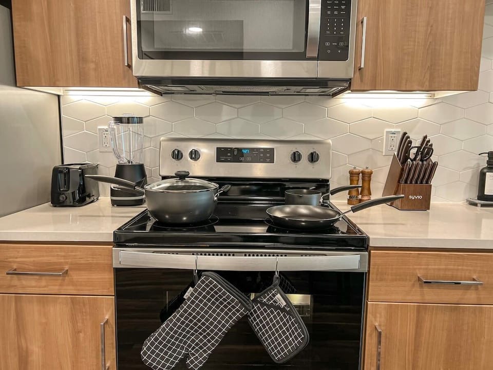 Fully equipped kitchen designed for extended stays, featuring a stovetop, microwave, refrigerator with freezer, blender, coffee machine, and complete dinnerware.
