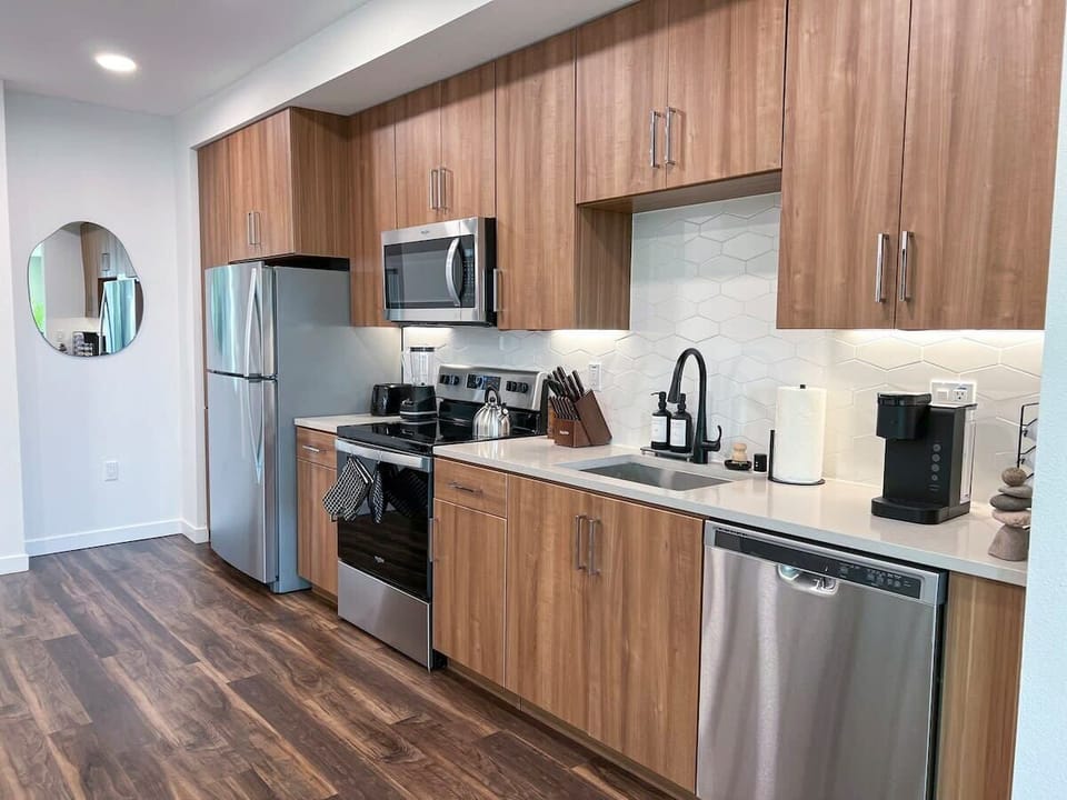 Fully equipped kitchen designed for extended stays, featuring a stovetop, microwave, refrigerator with freezer, blender, coffee machine, and complete dinnerware.