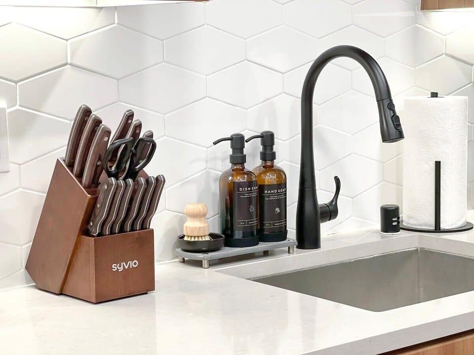 Modern kitchen ideal for extended stays, complete with sink and complimentary essentials: hand soap, dishwashing liquid, and paper towels.
