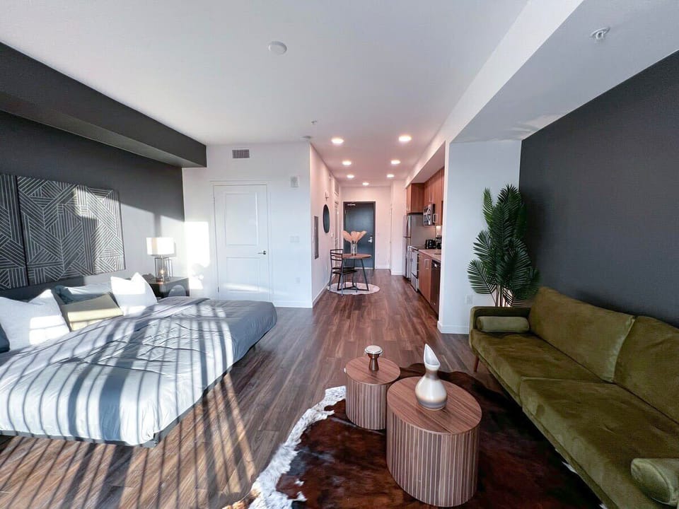 Contemporary urban living at its finest: a seamless blend of kitchen, dining, living, and bedroom areas in a modern, open-concept cosmopolitan-style apartment.