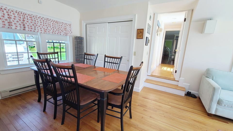 Family room has a dining table, sofa and large flat screen TV