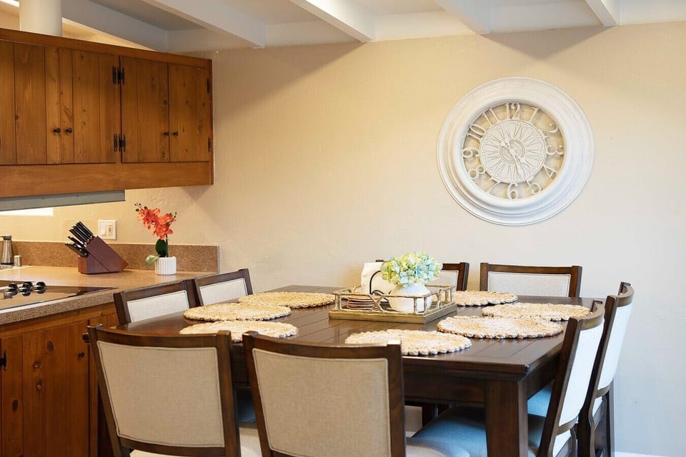 Dining table seats eight, framed by a large statement clock and sliding glass doors that open to the backyard.