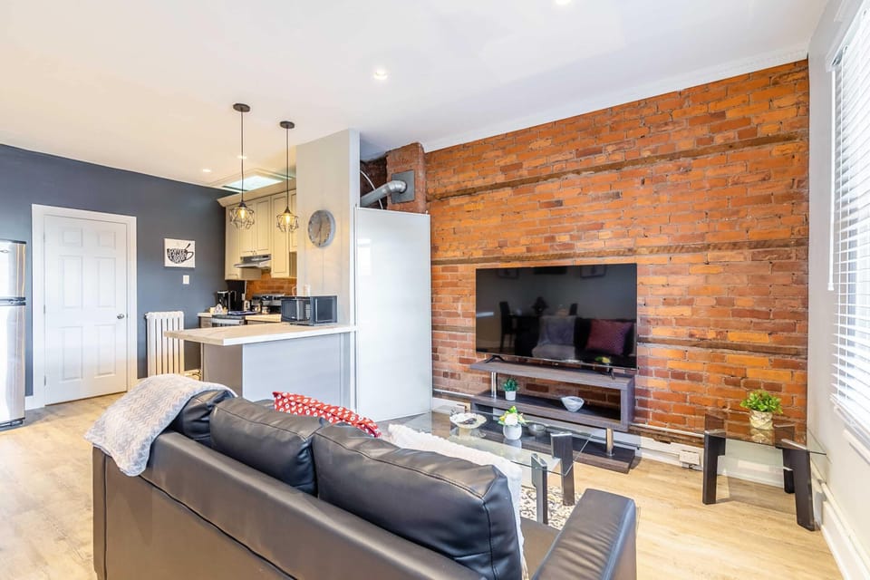 Spacious Living Area Featuring A Smart TV And Stylish Exposed Brick Wall