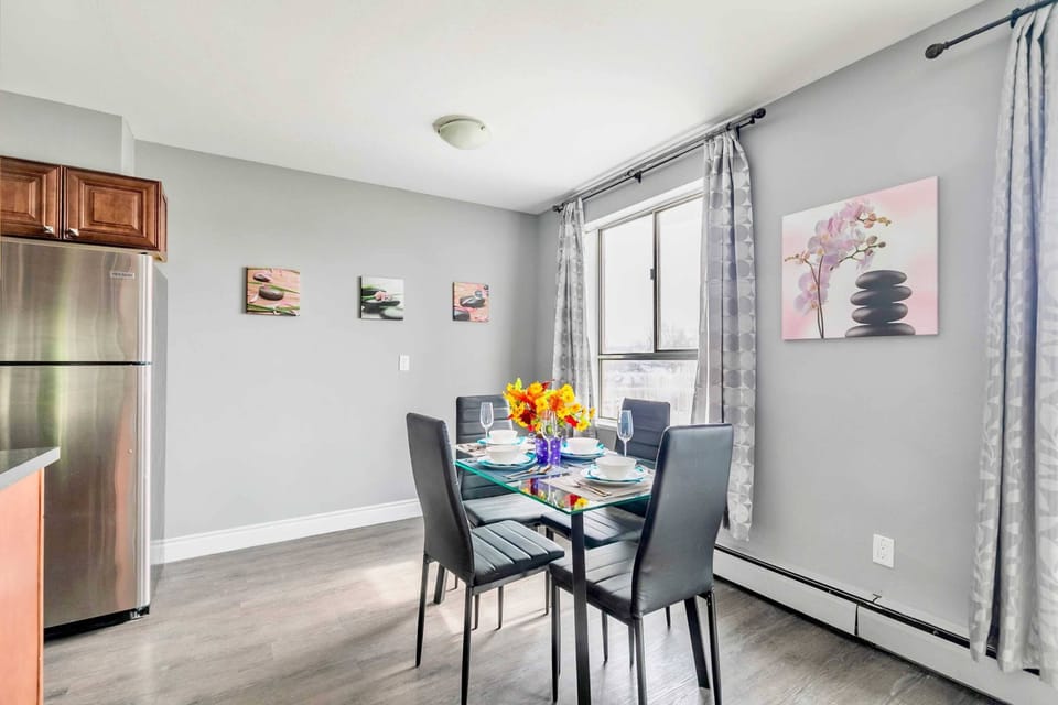 Bright Dining Area With A Glass Table, Stylish Decor, And Large Windows For Natural Light