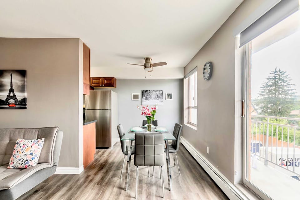 Bright Dining Area With A Glass Table, Comfortable Chairs, And Large Windows Overlooking The Balcony