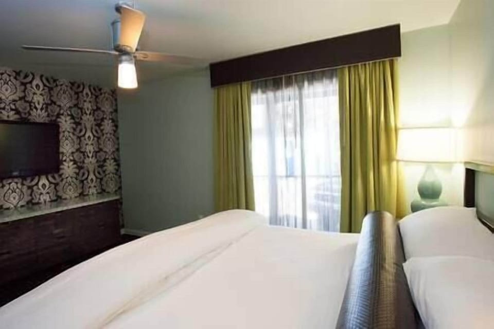 Bedroom includes flat screen TV, dresser, night stand, and access to patio