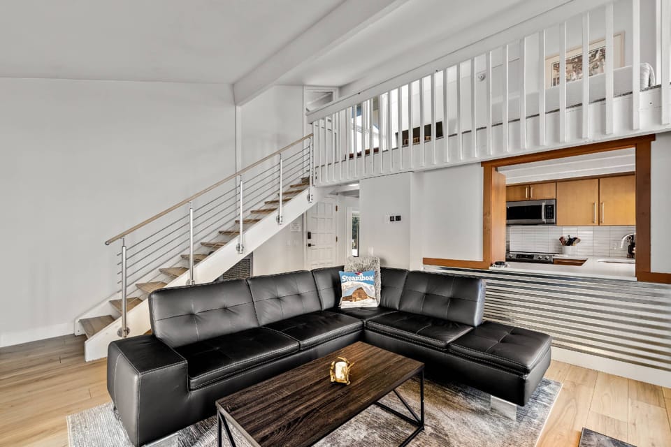 Living room with open pass through to the kitchen space, and views of upstairs loft TV area.