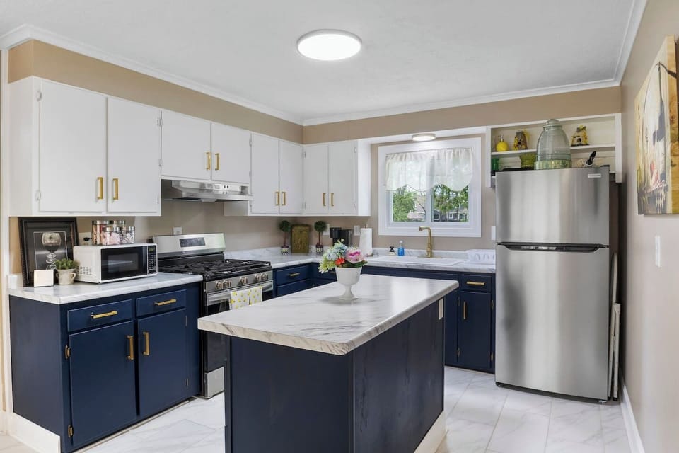Experience culinary delight in this spacious, modern kitchen featuring stylish navy blue cabinetry and state-of-the-art appliances, perfect for any chef.