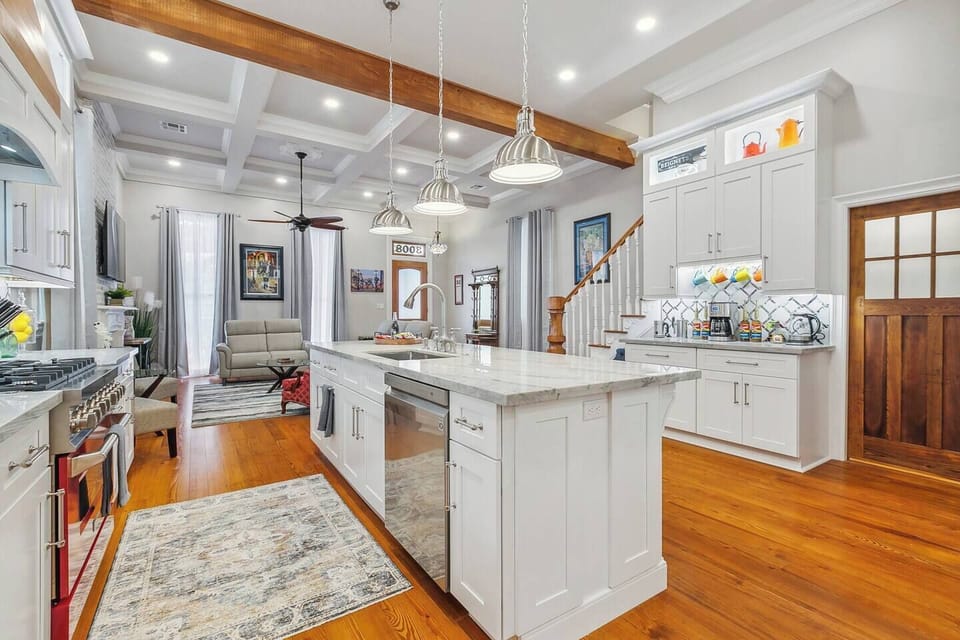 Spacious kitchen with high 12' ceilings, boasting a gas commercial range and a coffee bar complete with a frother, French press, drip coffee maker with syrups, and an electric tea kettle. There's also a separate walk-in pantry with a microwave.