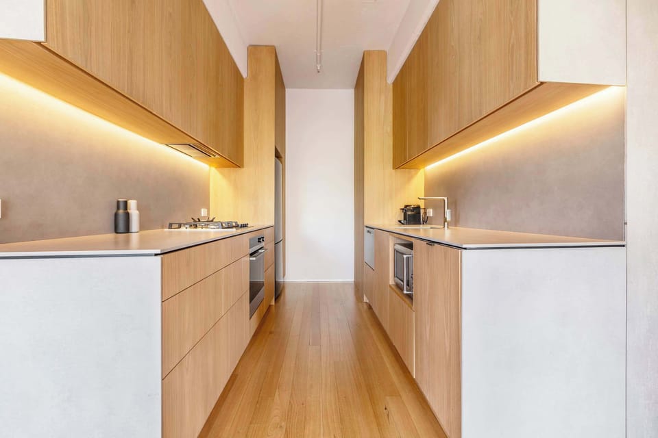 KITCHEN: Featuring rich Tasmanian Oak cupboards stocked with essentials and modern appliances, this kitchen is perfectly equipped for exploring Melbourne’s vibrant culinary scene or enjoying simple, delicious meals at home.
