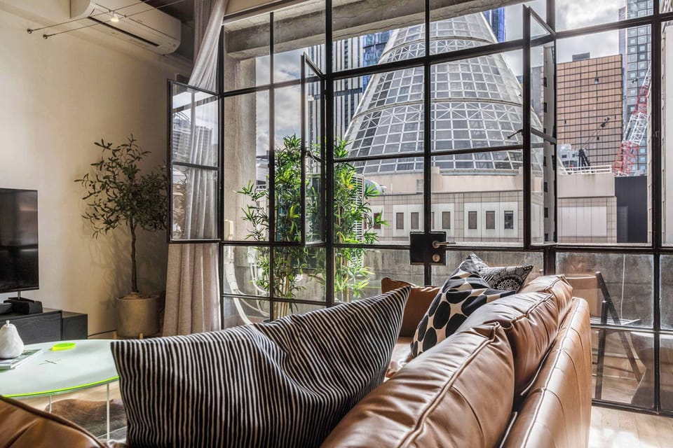 Stylish living room with natural light, city views, and a cozy leather sofa for relaxing
