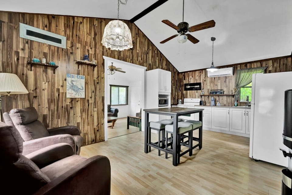 Open-concept living and dining area with rustic wood accents and high vaulted ceilings.