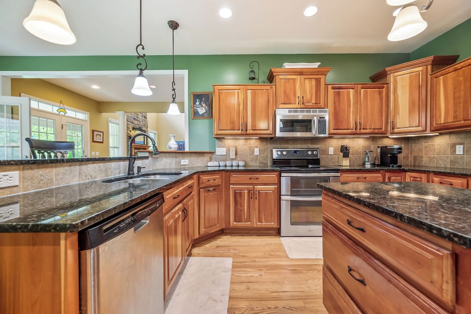 Spacious kitchen featuring granite countertops, rich wood cabinetry, and elegant finishes