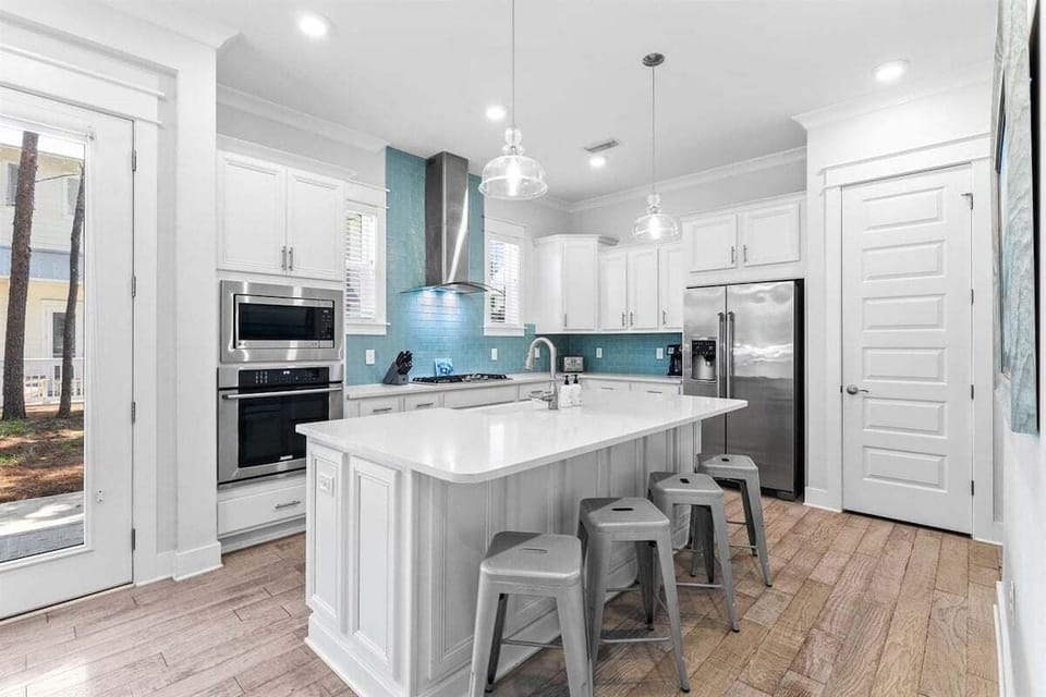 Open kitchen with stainless-steel appliances, and island seating for 4