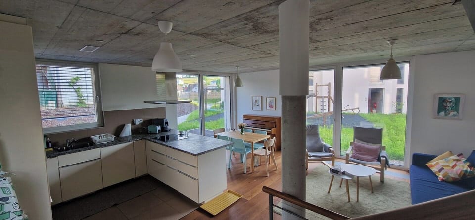 Wide view of kitchen with adjacent dining area, sitting area, kitchen window and 2 bay windows - flooded with daylight.
