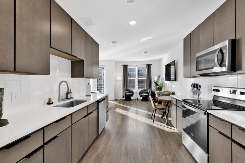 Modern kitchen with sleek stainless steel appliances and neatly arranged utensils, perfect for effortless cooking during your short-term rental stay.