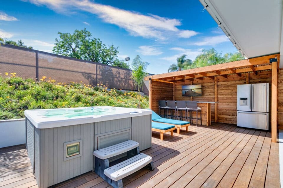 Jacuzzi on a spacious wooden deck, outdoor kitchen and bar
