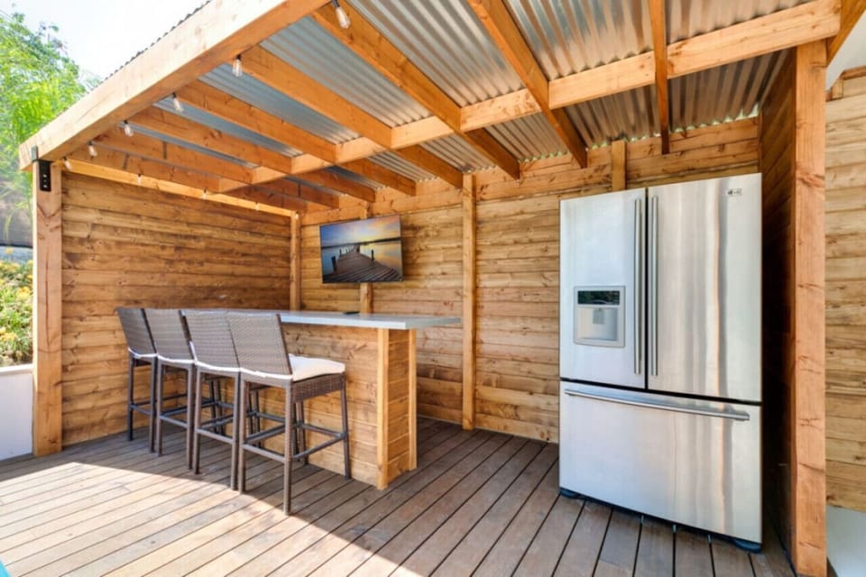 Outdoor bar with 4 hight chair, flat screen TV and refrigerator