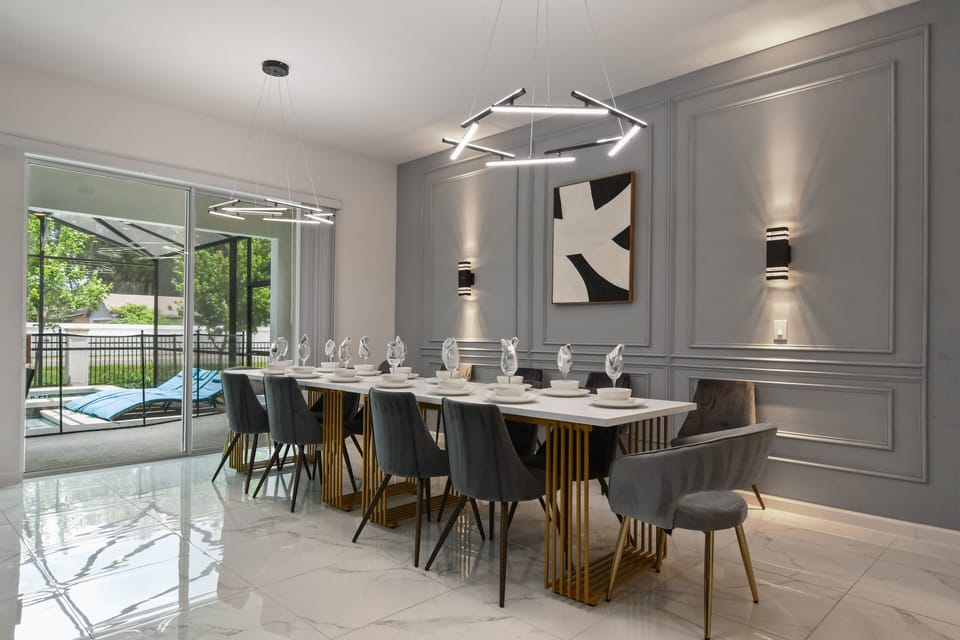 Stylish dining room with elegant decor, gold accents, and views of the private pool
