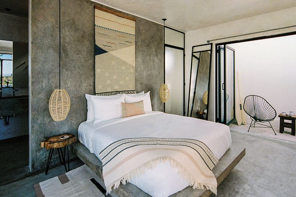 Sink into plush linens beneath warm woven pendant lights.