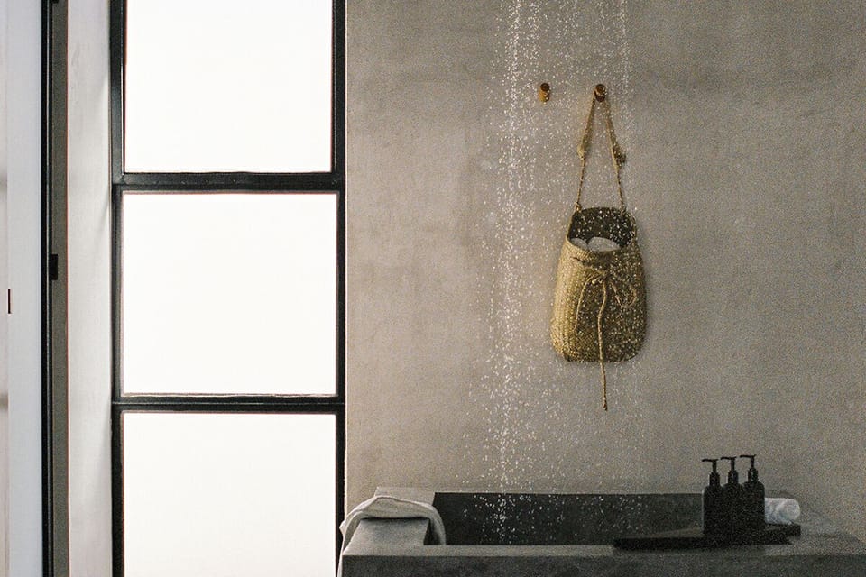 Rinse off under rainfall shower beside a sculpted soaking tub.