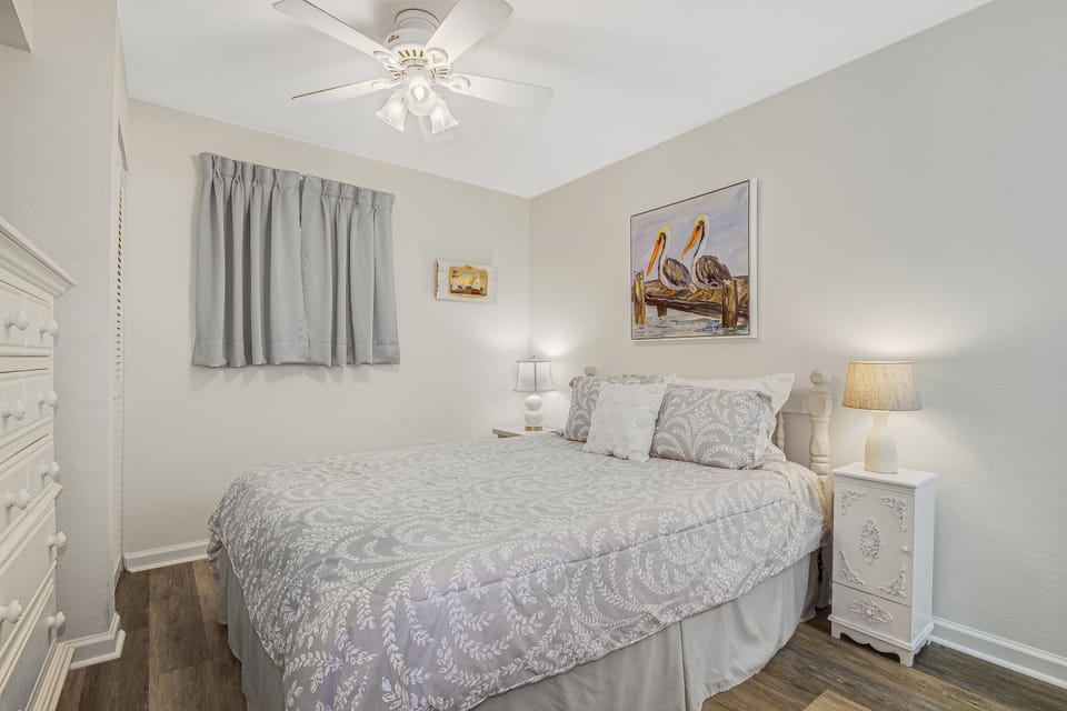 Settle into your peaceful bedroom retreat, where soft gray linens and charming coastal art create the perfect atmosphere for restful nights.