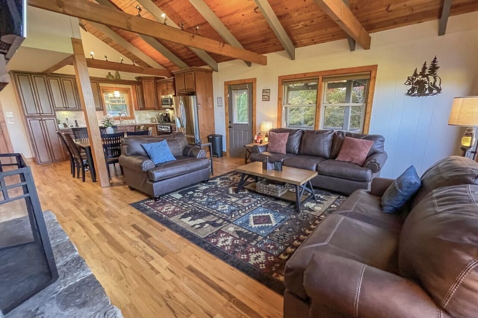 Gather beneath exposed beams in this warm open space with a stone fireplace, leather seating, and mountain lodge vibes.