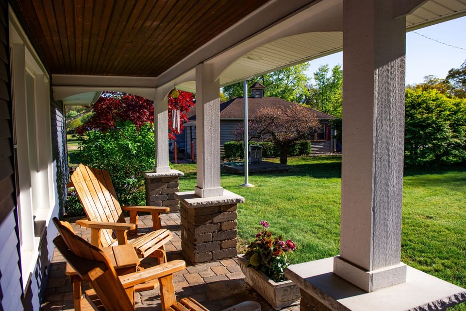 Relax on the covered front porch with Adirondack chairs and lush yard views