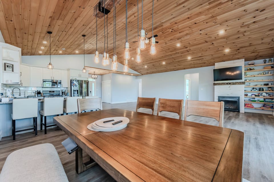 A close-up of the dining table reveals its rustic elegance, complemented by modern lighting fixtures. The spacious, open-plan design of the living area is perfect for family dinners and entertaining guests.