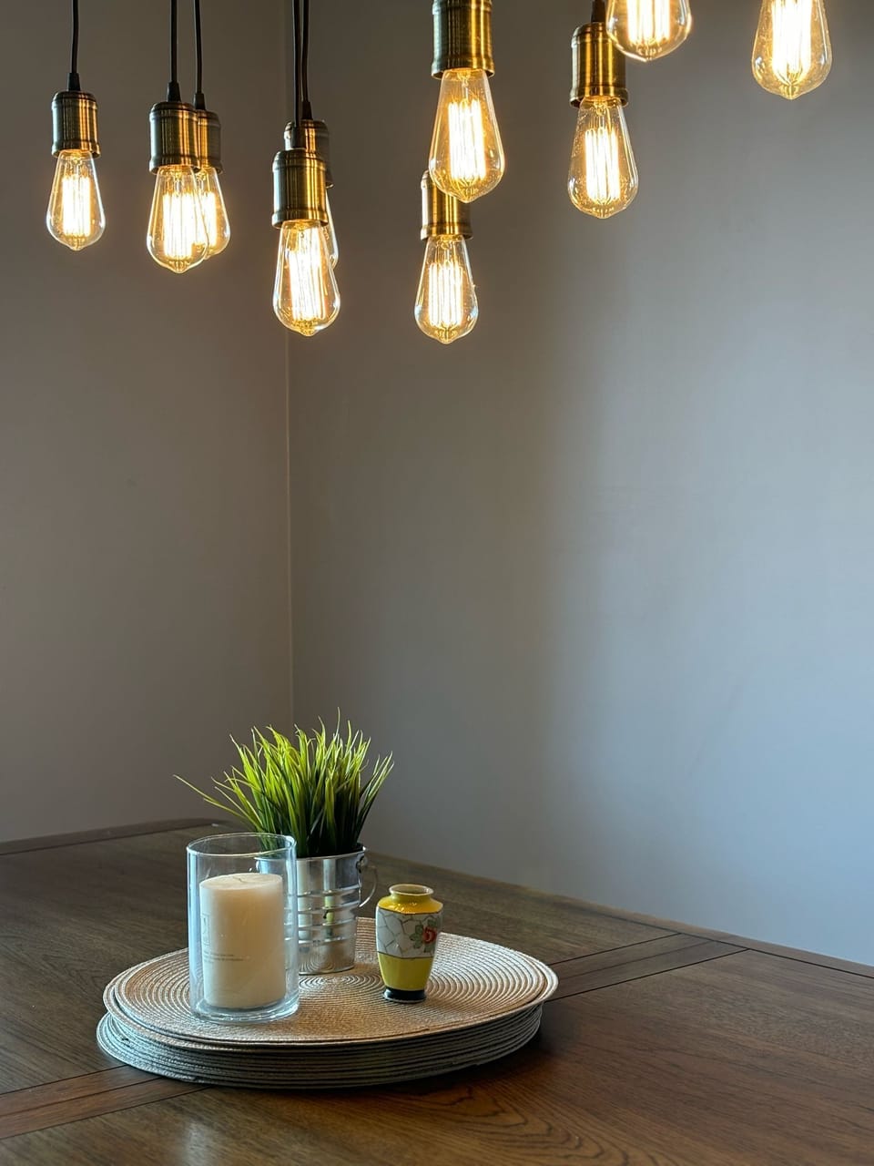 The dining table is beautifully set with simple, elegant decor. The hanging lights above add a warm glow, making it a perfect spot for intimate meals or gatherings.