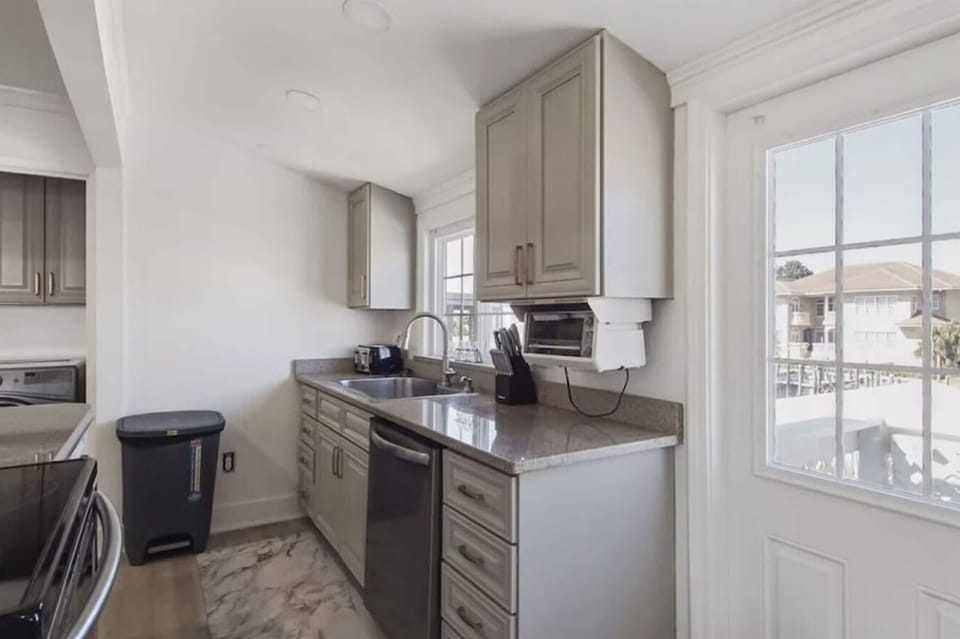 Step into your fully equipped kitchen with sleek gray cabinets, granite counters, and stainless appliances—perfect for preparing meals with harbor views.