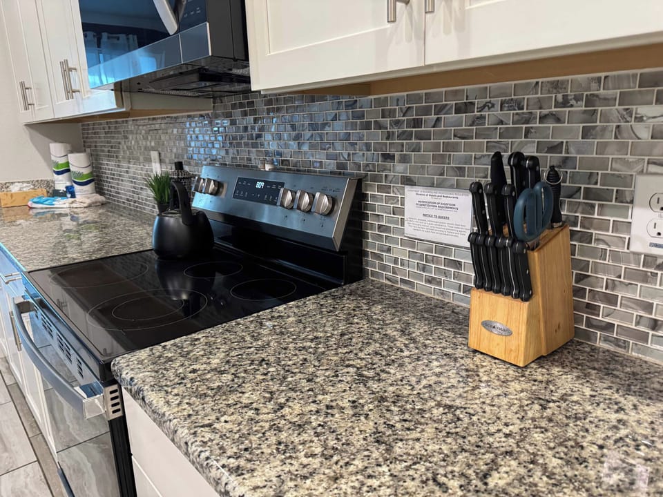 Private kitchen with a sleek electric range, granite countertops, and a distinctive gray mosaic backsplash.