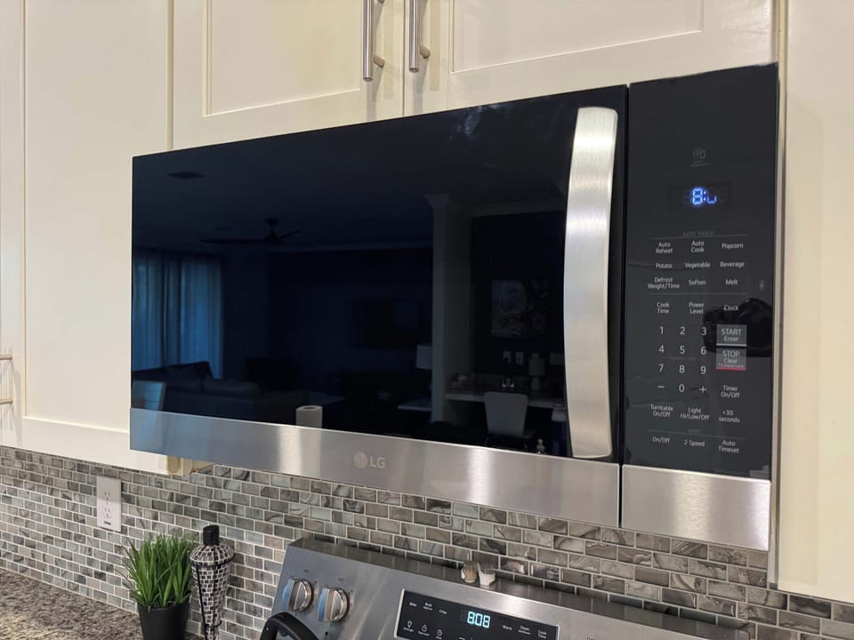 Private kitchen with stainless-steel appliances, white cabinetry, granite counters, and a distinctive gray mosaic-tile backsplash.