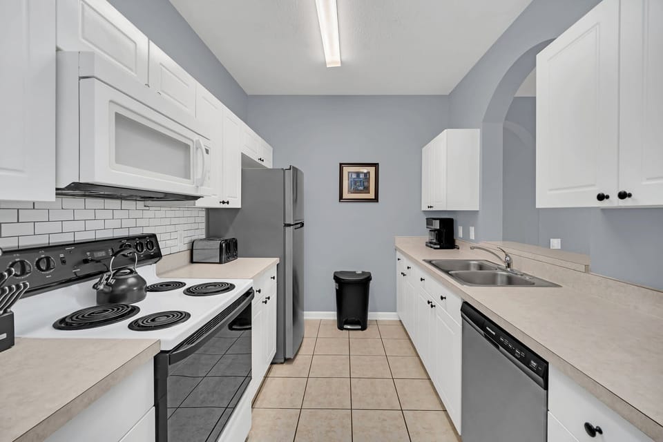 Modern kitchen with white cabinetry and stainless steel appliances for convenient cooking.