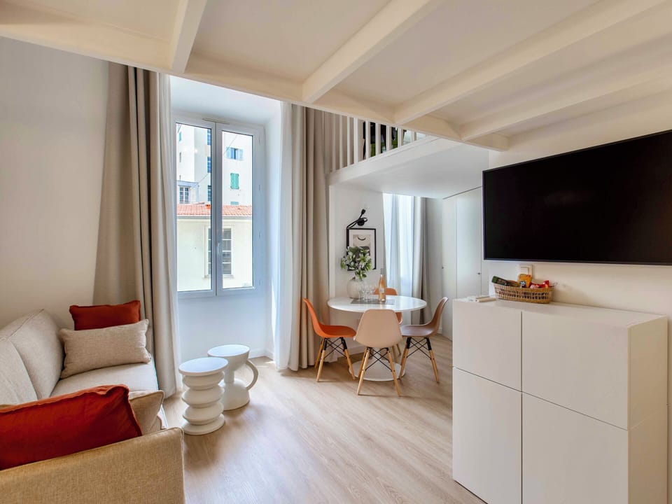 Living-room with table, open plan kitchen, sofa bed, TV and bathroom & toilet
