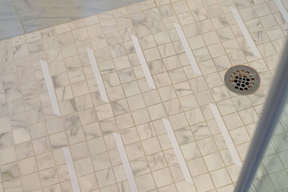 Modern tiled walk-in shower with anti-slip safety strips.