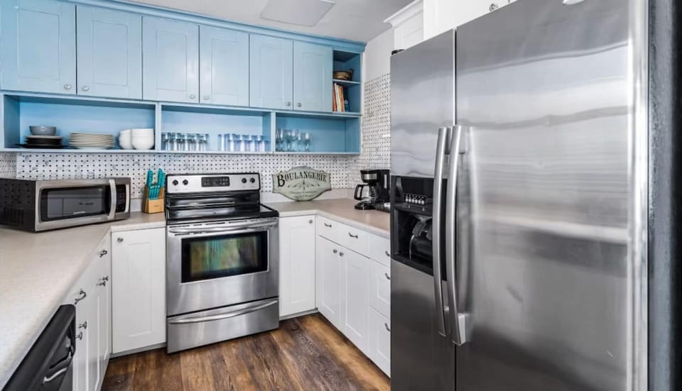 Cook your favorite meals in this bright, fully-equipped kitchen with stainless steel appliances and charming blue accents.