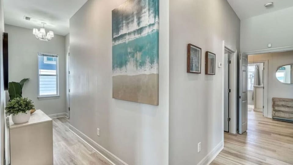 Step into your bright, modern hallway where coastal artwork and warm wood floors create a welcoming first impression.