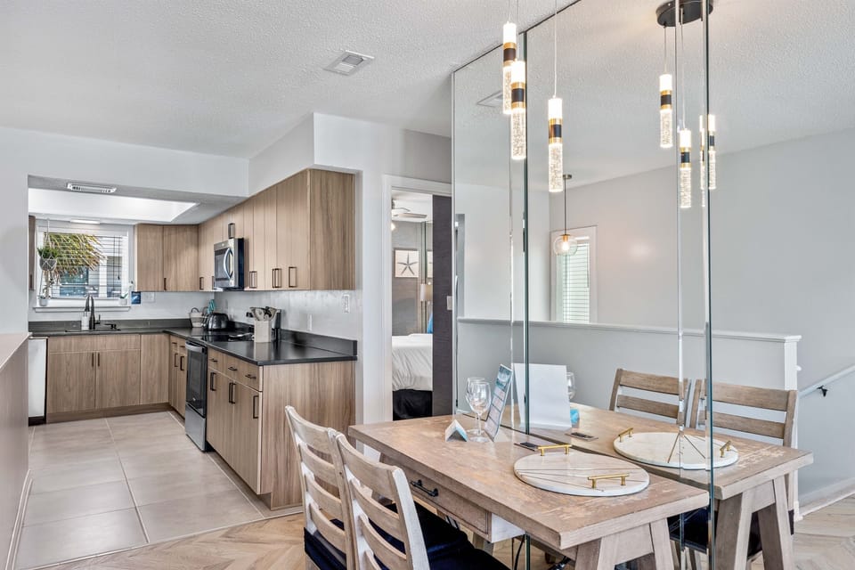 Gather around your sleek dining table beneath modern pendant lights, with a fully equipped kitchen perfect for preparing meals together.