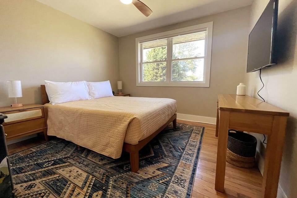 Queen bed with bedside lamps and Smart TV.