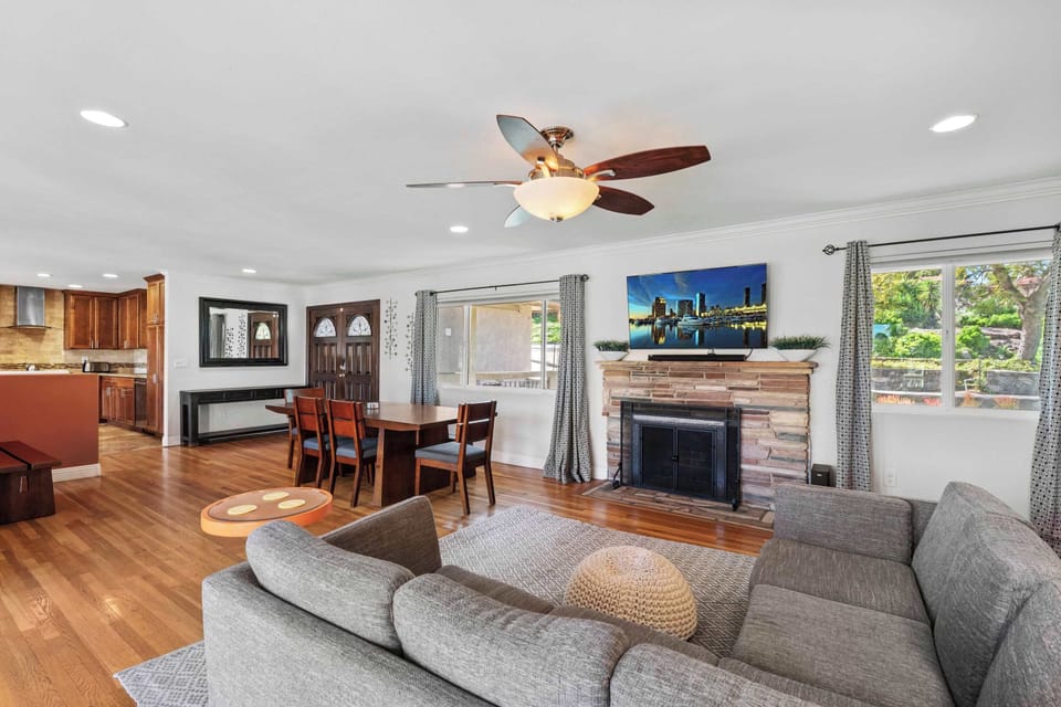 First Living Area (AC, ceiling fan, TV, large windows, dining area, fireplace)