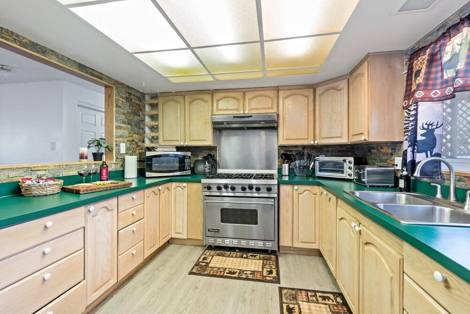 Built for groups who love to cook! A professional-grade 6-burner Viking gas range commands the center of this kitchen, featuring a stacked stone backsplash, a deep double sink, a microwave, a toaster oven, and generous counter space.
