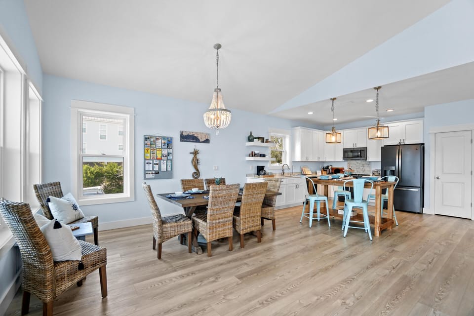 Gather around the elegant dining table or chat at the kitchen island in this bright, coastal-inspired space with stunning chandelier and water views.