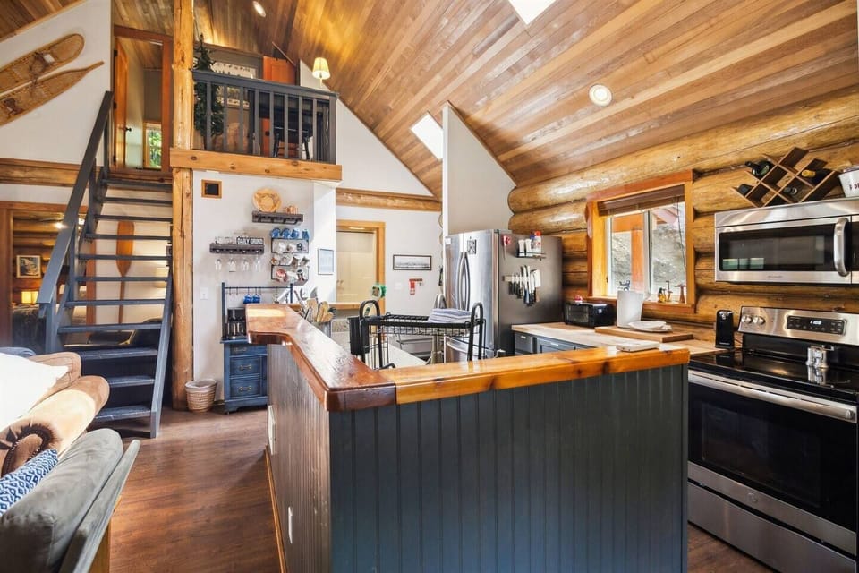 Charming and well-insulating log cabin walls outfit the main living and kitchen areas with a vaulted wood ceiling.