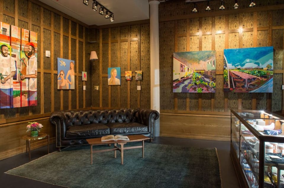 Artistic flair meets classic comfort in Hotel Old 77's lobby, featuring a plush leather sofa and vibrant gallery wall.