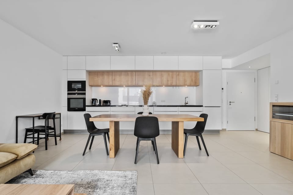 Step into a spacious, contemporary kitchen and dining area, featuring minimalist design and high-end appliances, ideal for both casual meals and gourmet cooking experiences.