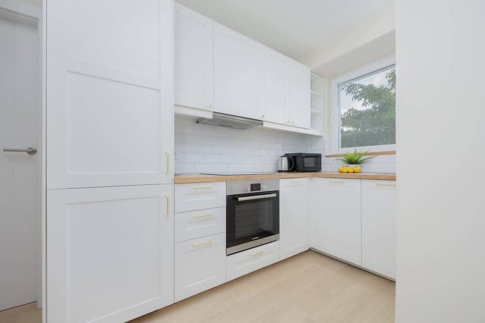 A modern white kitchen with wood countertops and built-in appliances. Compact, clean, and fully equipped.