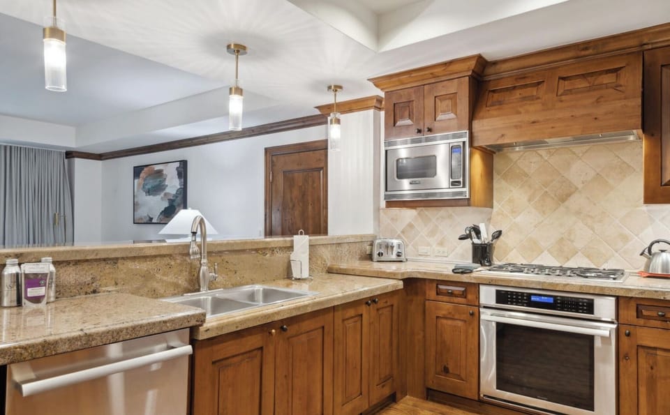 Open kitchen toward living area with dishwasher, sink, microwave, gas stove/oven